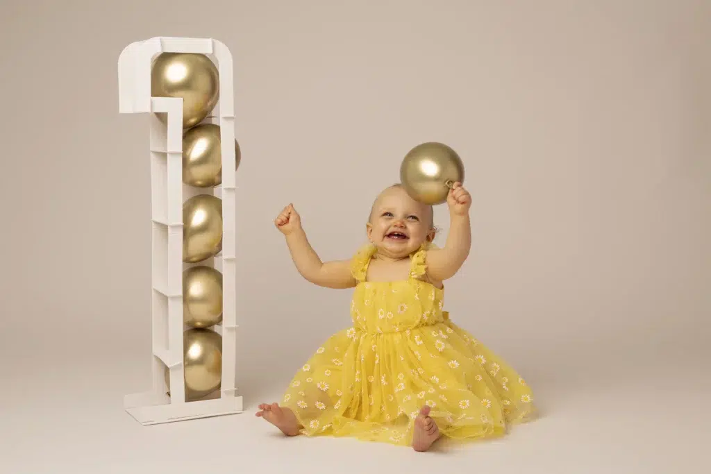 Petite fille en robe jaune avec ballon pour une séance photo anniversaire en studio Essonne