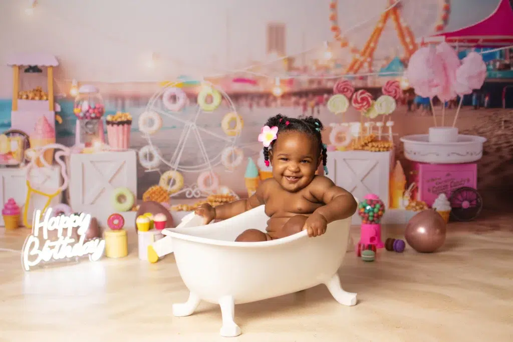 Petite fille dans un bain de lait lors d'une séance smash the cake anniversaire avec décor fête foraine en studio photo Essonne